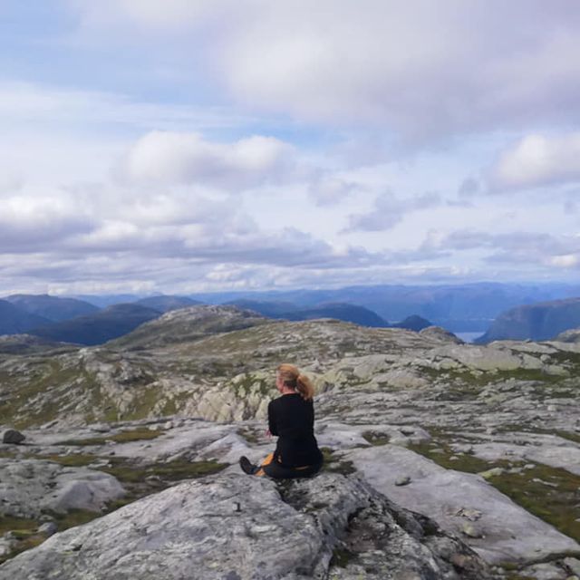 Dame sitter på fjelltopp